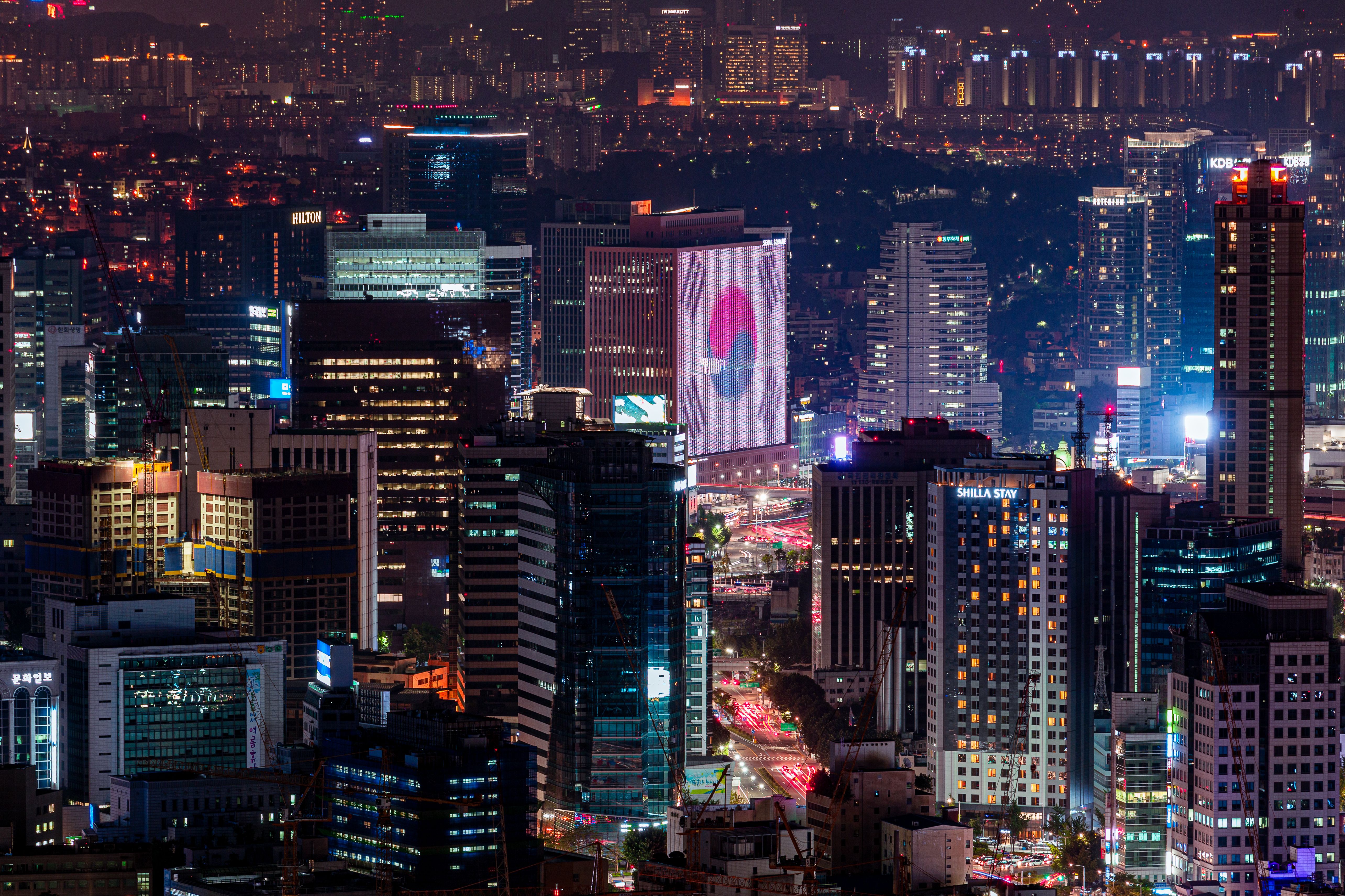 首尔夜景，高楼灯光璀璨，韩国国旗电子屏点亮城市天际线。